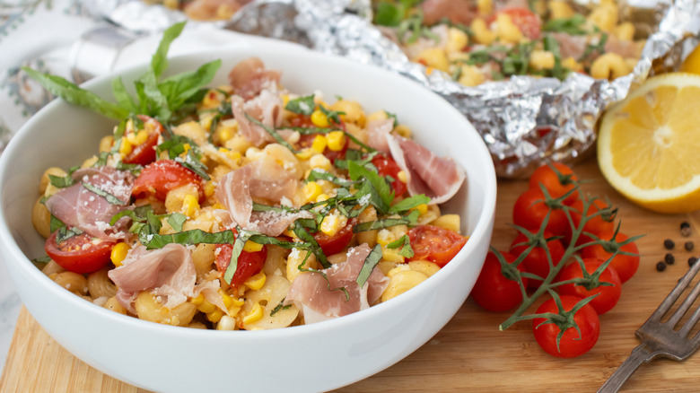 Side shot of a bowl filled with pasta and a foil pouch of pasta in the background