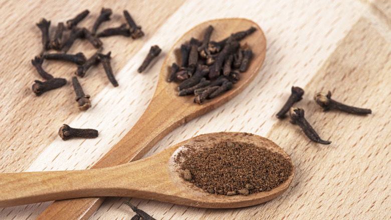 Two wooden spoons, one with ground gloves, the other with whole cloves