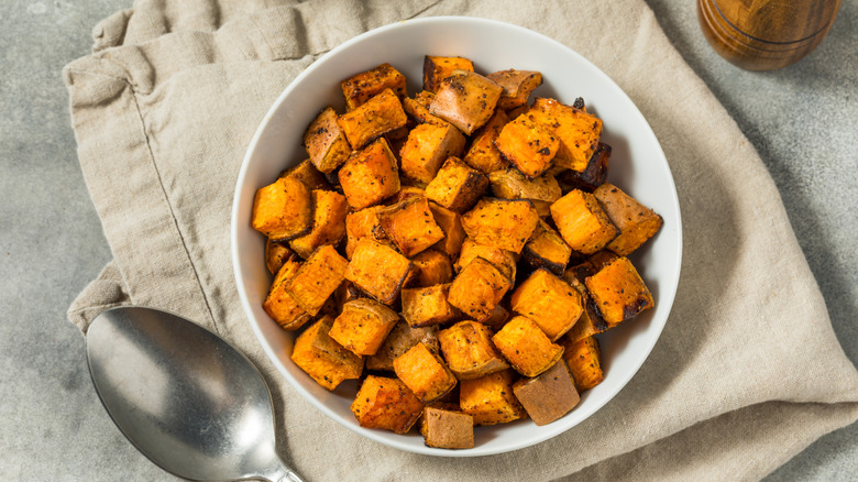 Cubed sweet potatoes in a white bowl on top of a tan cloth