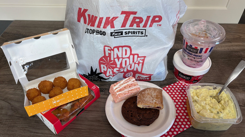 Kwik Trip grocery bag with assorted hot, cold, and bakery items on wooden cutting board