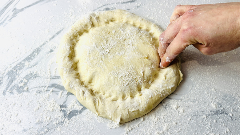 Shaping pizza dough on table