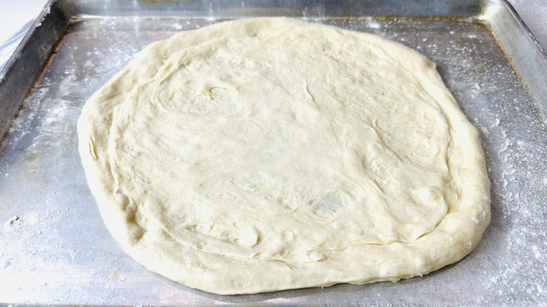 Pizza dough on floured baking sheet