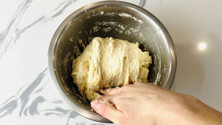 Folding pizza dough in bowl