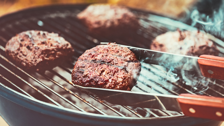 Tongs flipping veggie burger on the grill