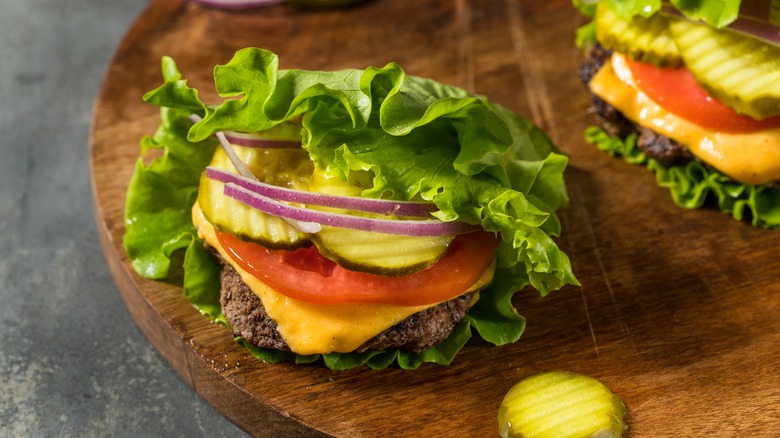A bun-less burger with lettuce instead of bread, on a wooden board