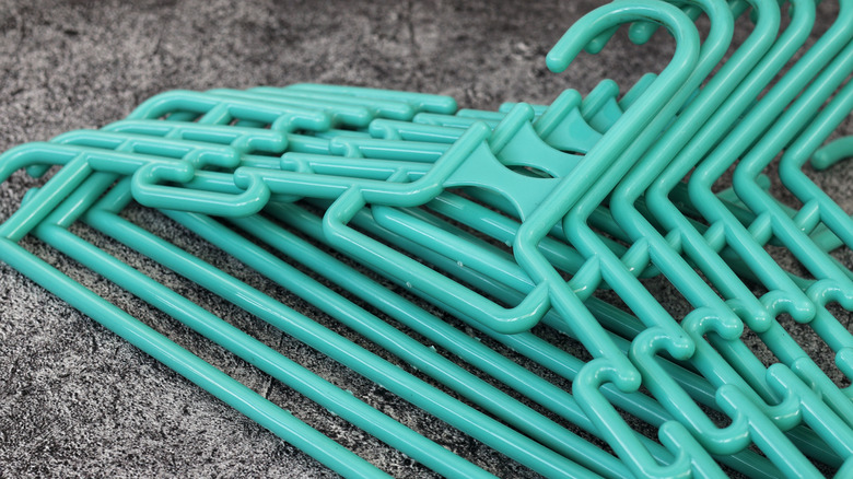 pile of teal plastic clothes hangers on a carpeted floor