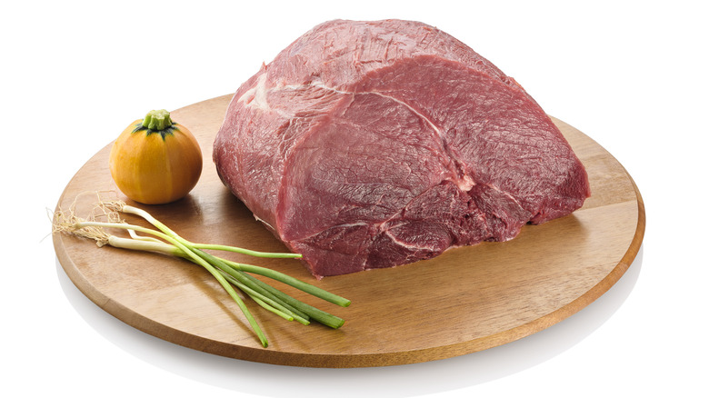 A cut of raw beef knuckle on a cutting board