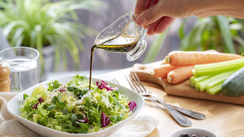 vinaigrette being poured over a salad bowl
