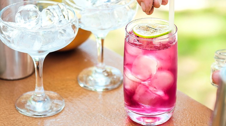 A vodka soda with berry-colored syrup and a slice of fresh lime.