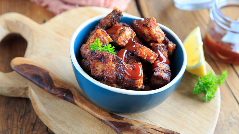 A bowl of pork belly burnt ends with barbecue sauce.