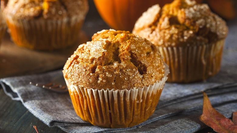 Close-up of a pumpkin muffin with a coarse sugar topping on a folded cloth napkin