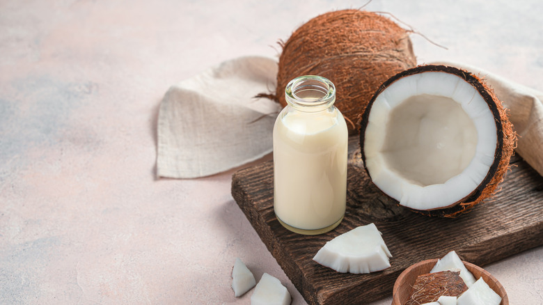 A coconut half alongside a jug of coconut milk.