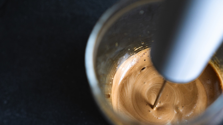 Frother whipping coffee in metal cup