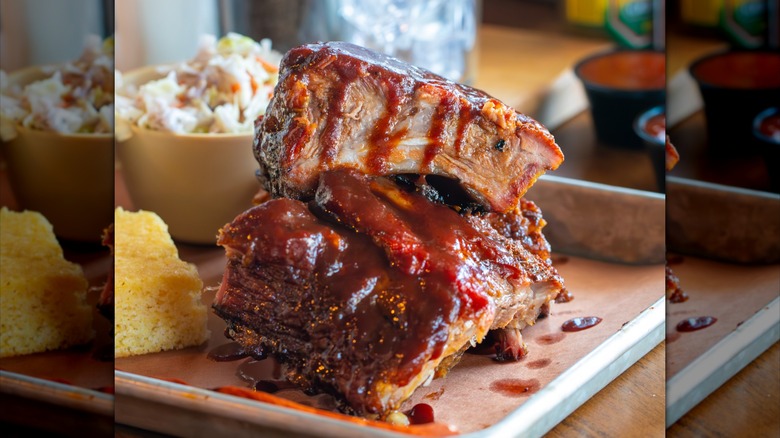 Barbecue ribs on a metal tray with cornbread and coleslaw