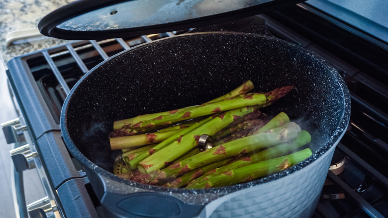 Asparagus being steamed in a pot.