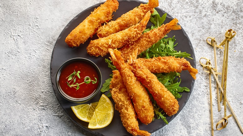 A plate of breaded shrimp with dip and a lemon slice