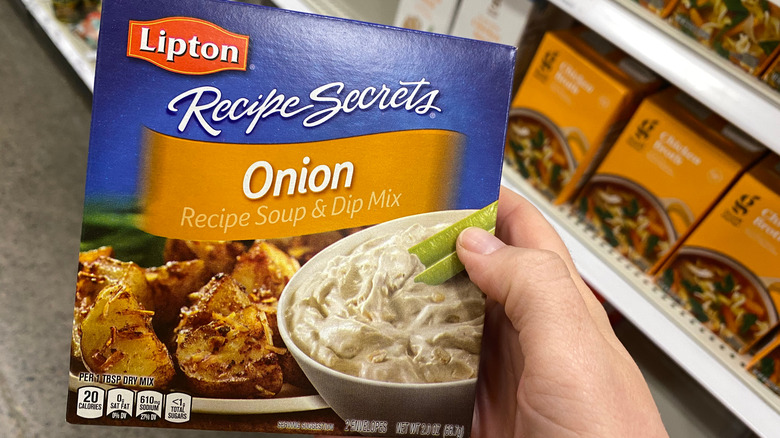 Hand holding a box of Lipton Onion Soup Mix