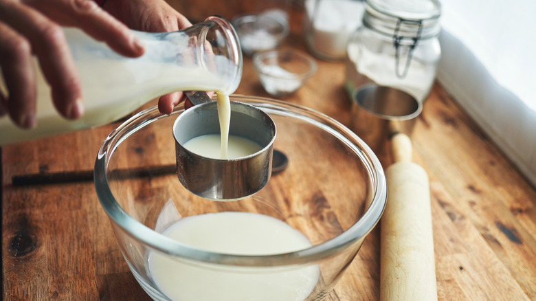 Person measuring buttermilk in a bowl.