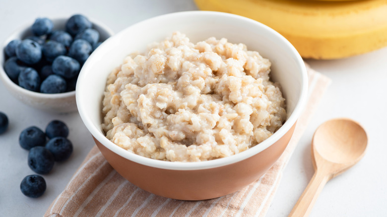 Plain oatmeal in a bowl with fresh blueberries on the side.