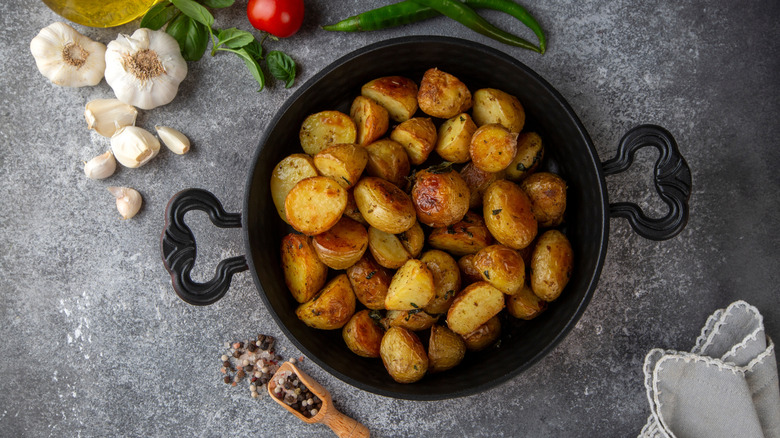 Roasted potatoes in cast iron pan with spices and garlic on the side