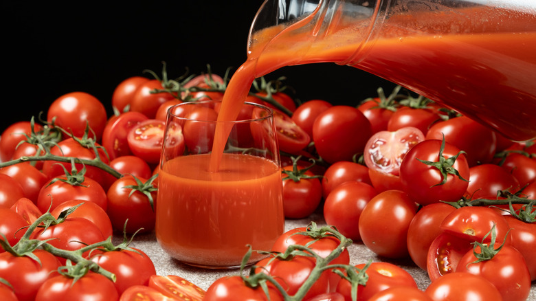Pitcher pouring tomato juice in a glass