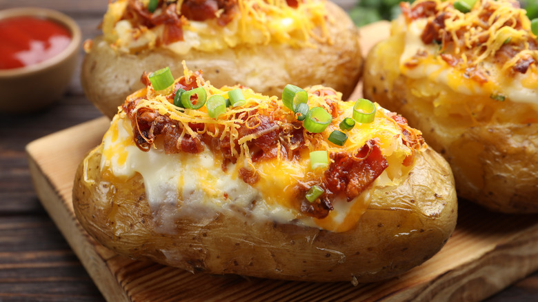 Tasty stuffed baked potatoes served on wooden table, closeup