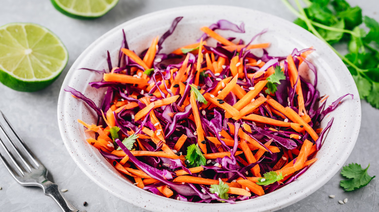 Red Cabbage and Carrot Slaw salad with cilantro and sesame seeds on stone background