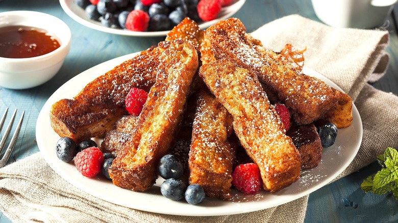 White plate piled high with French toast sticks and fresh berries