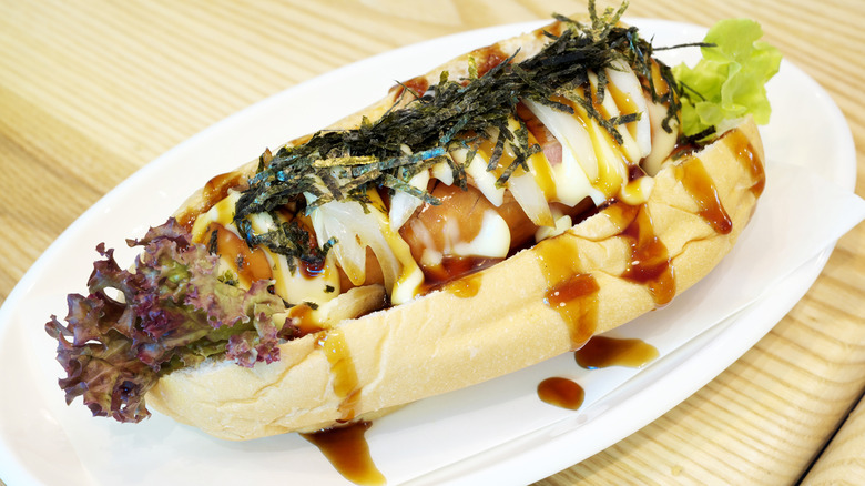 A fusion Japanese hot dog sits on a plate