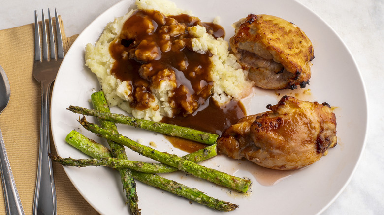 Mashed potatoes with gravy, plus chicken and asparagus on the side