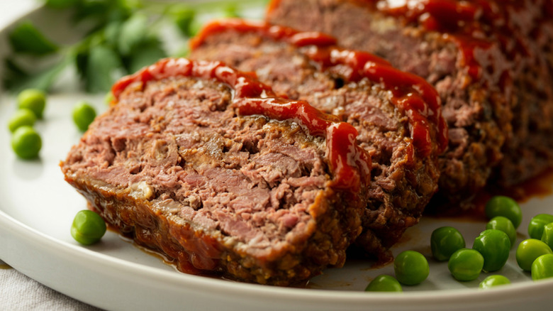 Slices of meatloaf on plate with peas