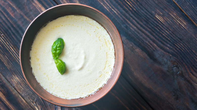 A bowl of creamy Alfredo sauce topped with fresh garnish