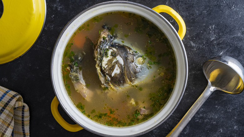 A pot containing soup with a fish head in it