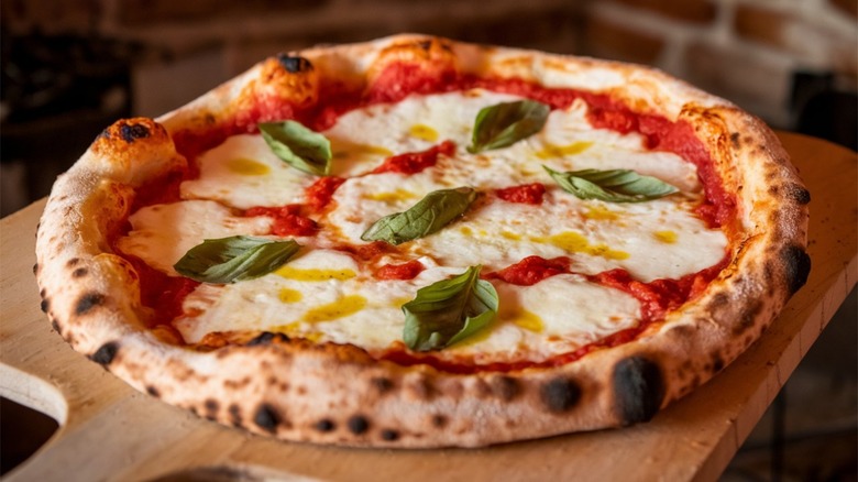 A freshly baked Neapolitan-style Margherita pizza on a wooden board.