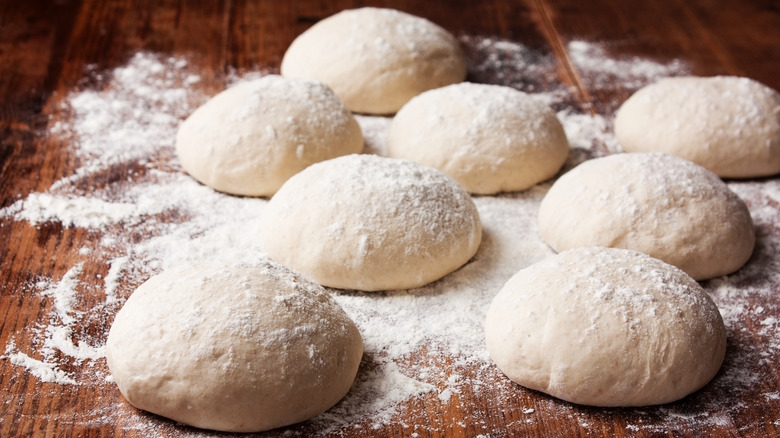 Pizza dough balls on a wooden surface.