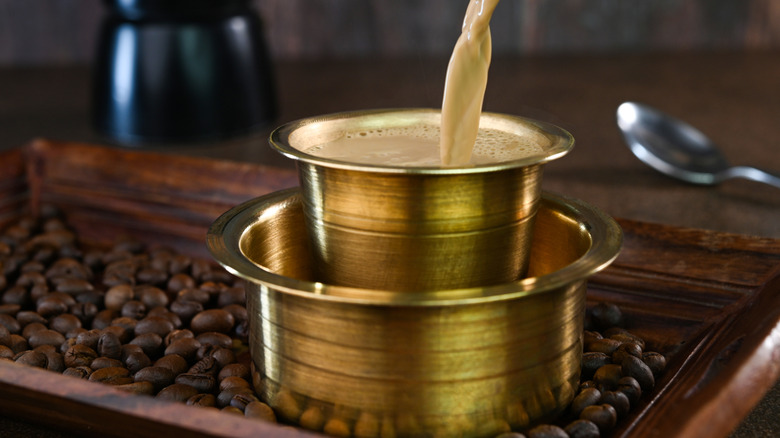 Indian filter coffee sitting atop coffee beans.