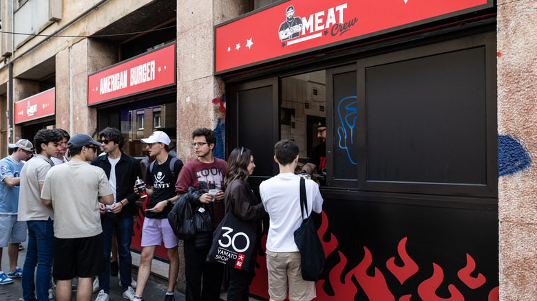 People line up outside of a restaurant.