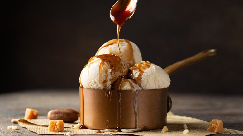 Spoon drizzling sauce over ice cream