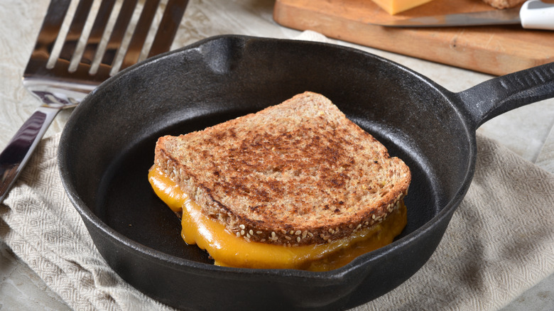 Gooey grilled cheese sandwich in a cast iron pan over a napkin