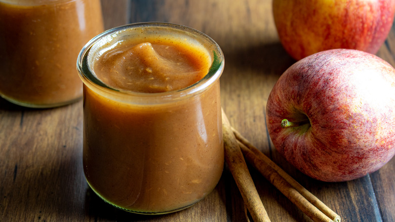 Jar of apple butter with cinnamon and apples
