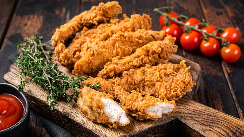 Fried chicken tenders on a wooden cutting board