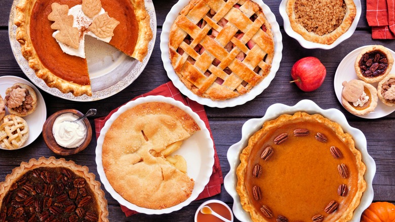 A variety of pies displayed on a wood surface.