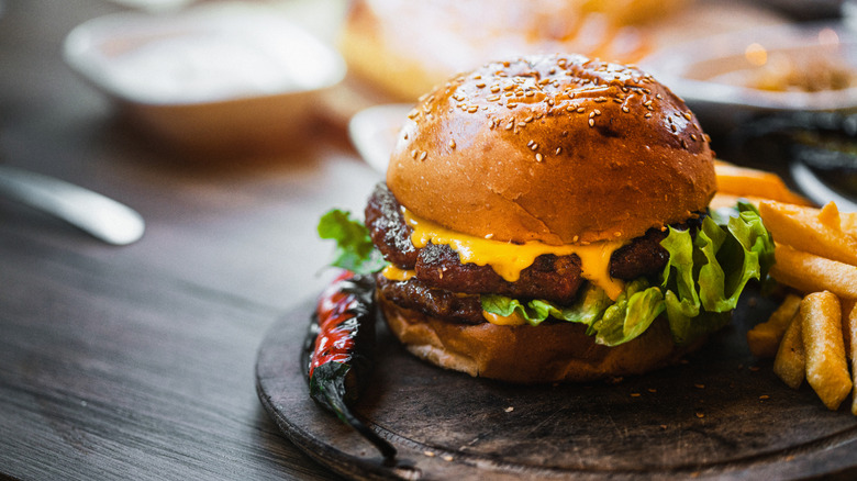 A double burger with cheese is plated with French fries.