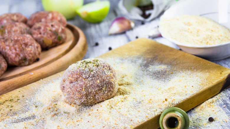 Meatball rolled in breadcrumbs on a wooden board