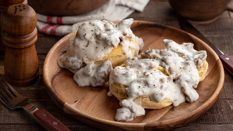 a wooden plate with biscuits and gravy.