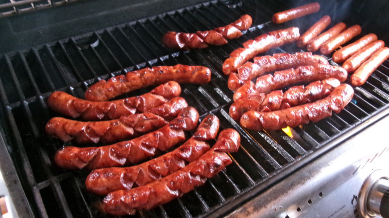 Hot dogs cooking on a grill during a summer cookout