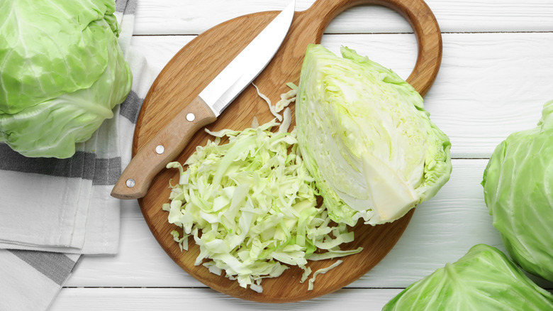 Fresh chopped cabbage on a wooden cutting board with a knife