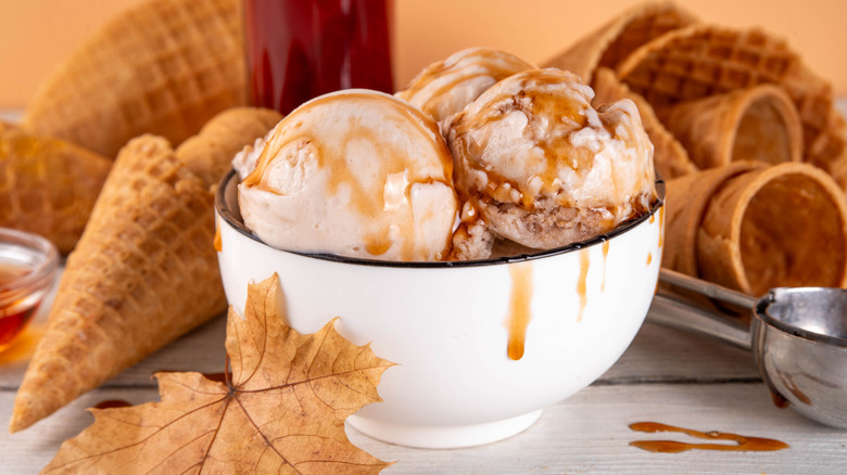 Bowl of ice cream with drizzle and cones in background