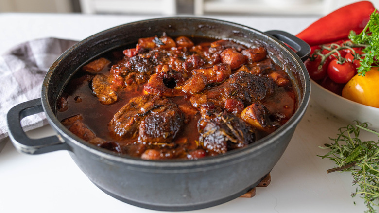 Bone-in beef shank with gravy and thyme in a dish with vegetables
