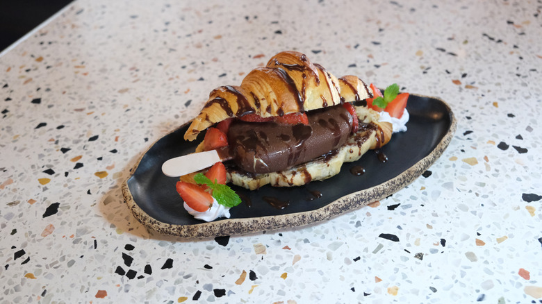 A chocolate-drizzled croissant stuffed with a Magnum ice cream bar and strawberries